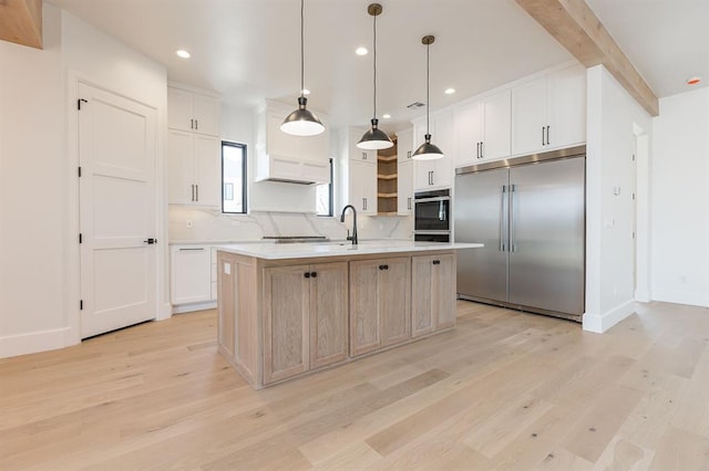 2009 Wiregrass Dr, Edmond, OK 73025 - kitchen featuring stainless steel appliances, light wood-type flooring, light countertops, open shelves, and a kitchen island with sink