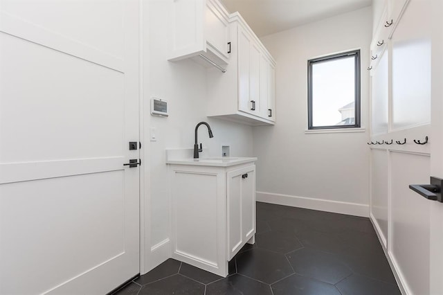 laundry room featuring cabinets, hookup for a washing machine, dark tile patterned flooring, and sink