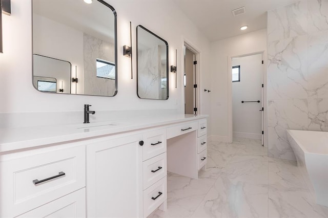 bathroom with vanity, a tub to relax in, and tile walls