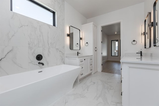 2009 Wiregrass Dr, Edmond, OK 73025 - full bathroom featuring a freestanding tub, marble tiled floors, two vanities, and baseboards