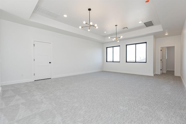 unfurnished room with a chandelier, light carpet, and a tray ceiling