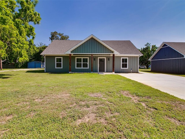 view of front of house featuring covered porch, an outbuilding, and a front yard