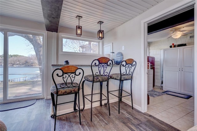 dining room featuring light hardwood / wood-style floors, a water view, and wooden ceiling