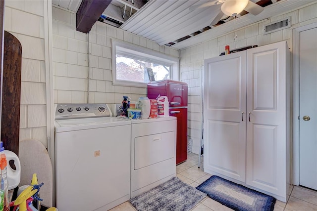 laundry area featuring washer and clothes dryer, ceiling fan, light tile patterned floors, and tile walls