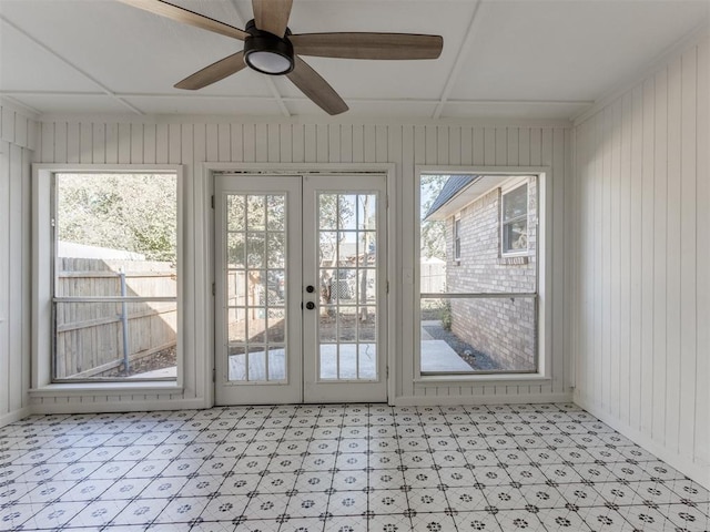 interior space with ceiling fan, a healthy amount of sunlight, wooden walls, and french doors