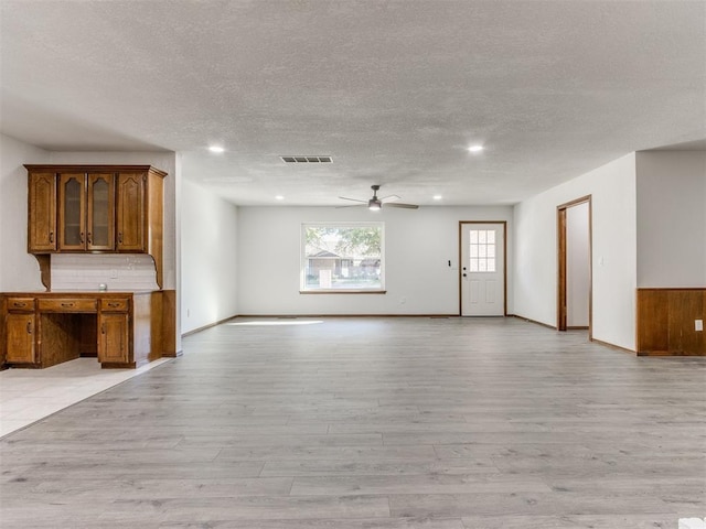 unfurnished living room with ceiling fan, light wood-type flooring, and a textured ceiling