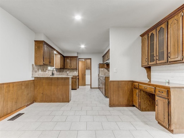 kitchen with kitchen peninsula, decorative backsplash, and sink