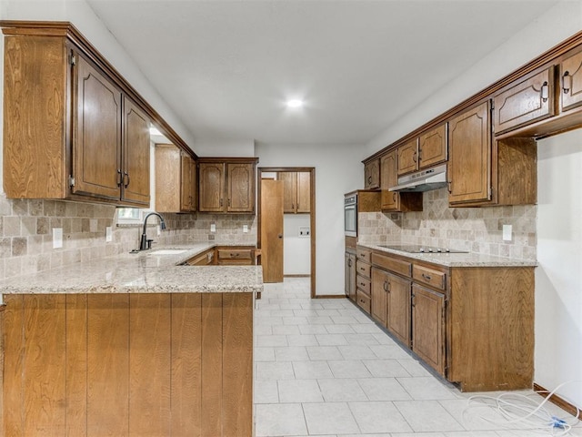 kitchen with sink, tasteful backsplash, light stone counters, kitchen peninsula, and black electric cooktop