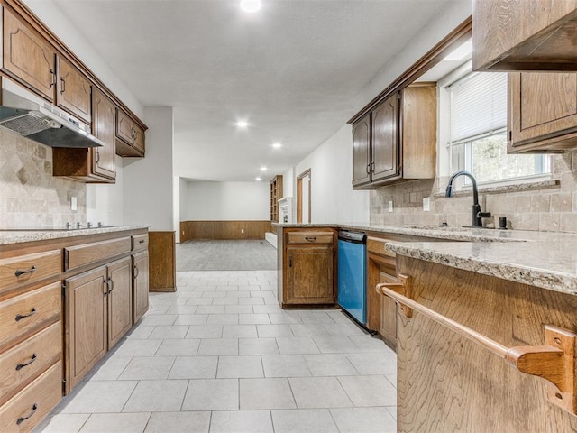 kitchen featuring kitchen peninsula, tasteful backsplash, light stone counters, sink, and dishwasher