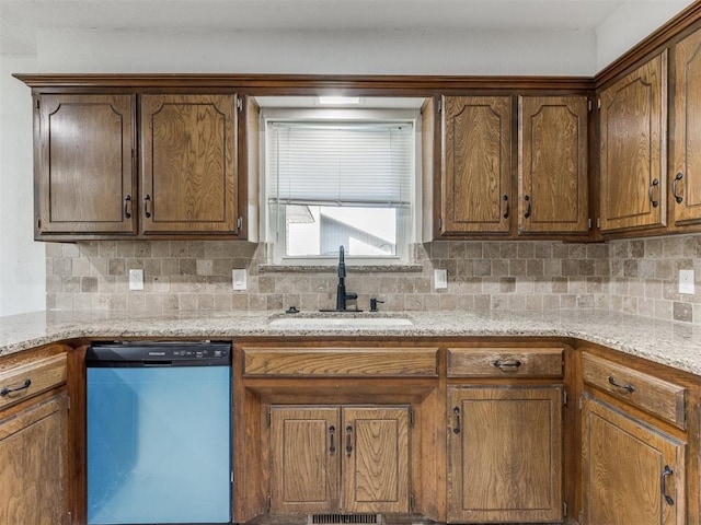 kitchen with dishwasher, tasteful backsplash, light stone counters, and sink