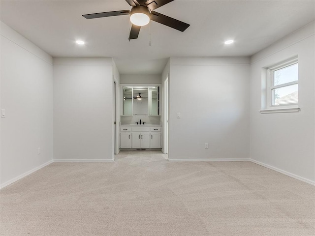 carpeted empty room featuring ceiling fan and sink