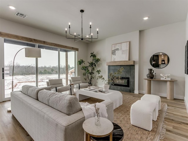 living room with recessed lighting, visible vents, a tiled fireplace, and wood finished floors