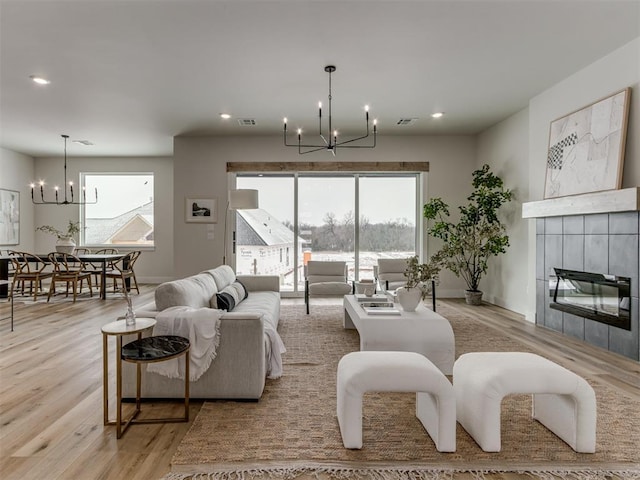 living area with visible vents, light wood-style flooring, a fireplace, a chandelier, and recessed lighting