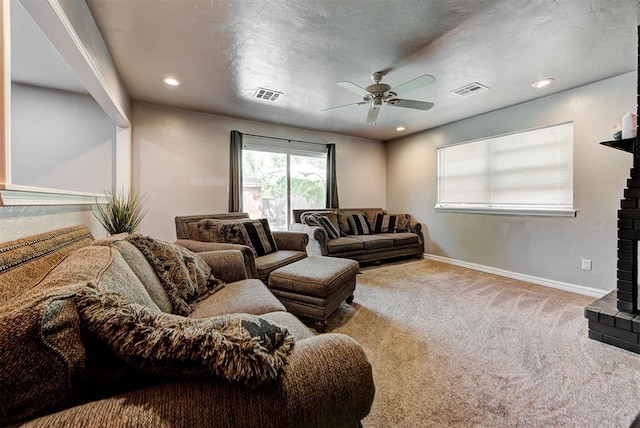 living room featuring carpet, ceiling fan, and a fireplace