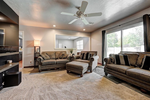 carpeted living room featuring ceiling fan and a textured ceiling