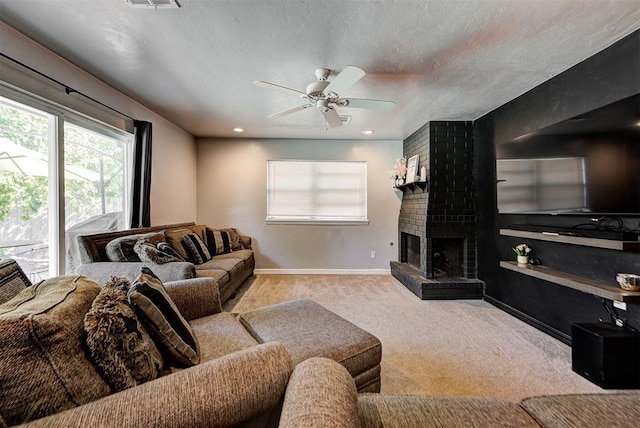 carpeted living room with a textured ceiling, ceiling fan, and a fireplace