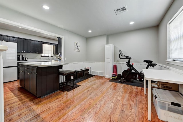 kitchen with a kitchen breakfast bar, light hardwood / wood-style floors, and white fridge