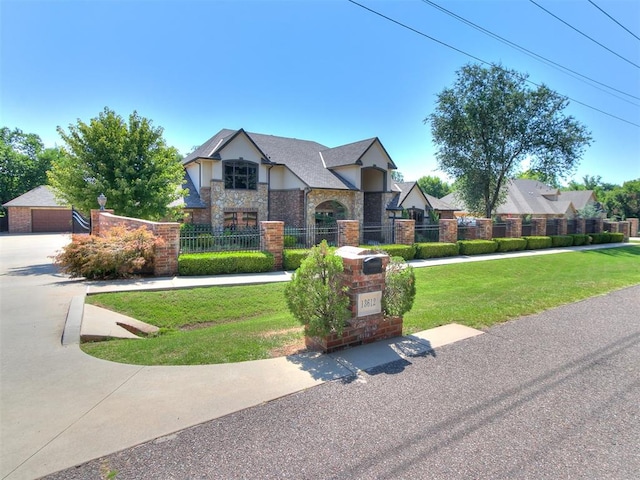 tudor home with stone siding, a fenced front yard, an outdoor structure, and a front yard