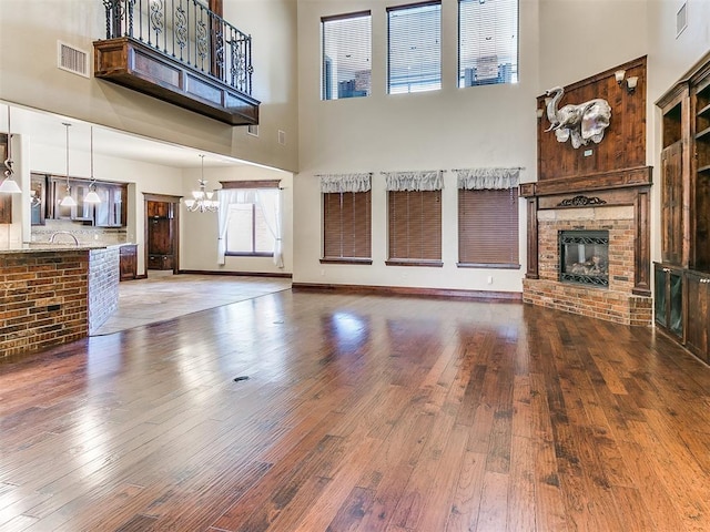 unfurnished living room with wood-type flooring, a high ceiling, and a brick fireplace