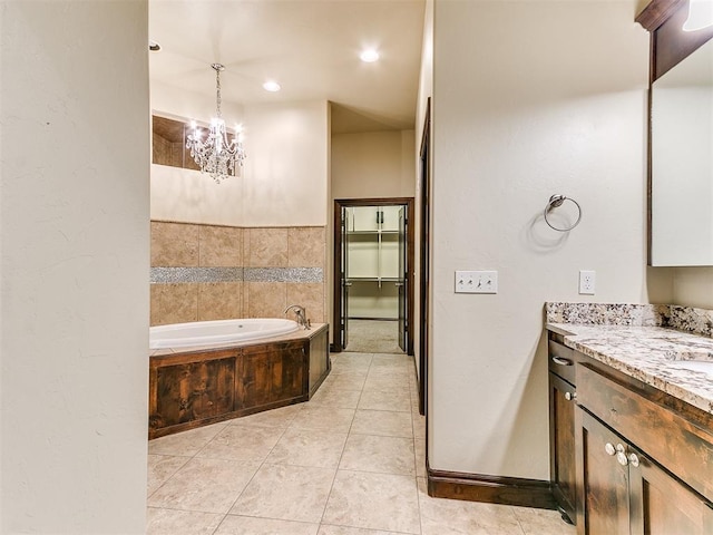 bathroom with a chandelier, a garden tub, vanity, and tile patterned floors