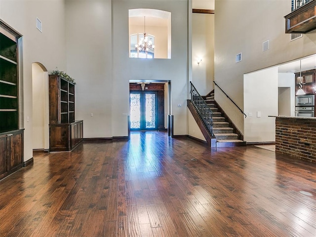 foyer entrance with arched walkways, hardwood / wood-style flooring, visible vents, an inviting chandelier, and stairs