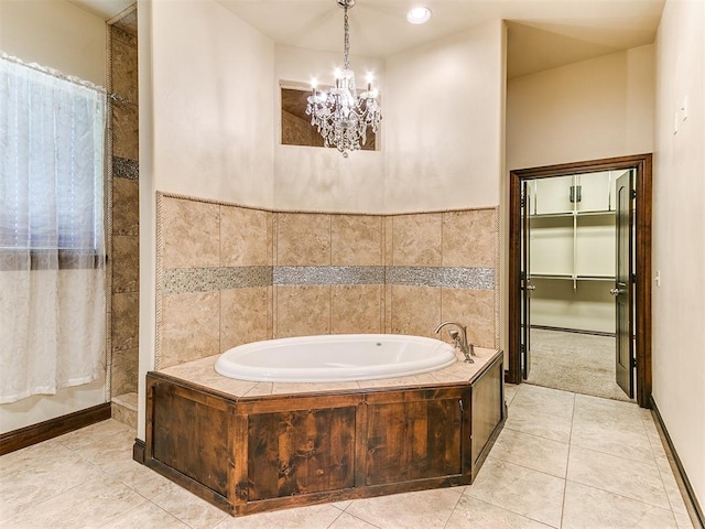 bathroom with a chandelier, tile patterned flooring, and a relaxing tiled tub