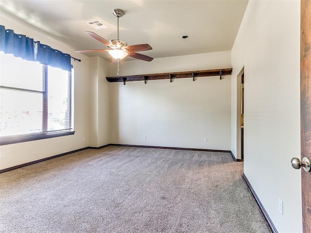 carpeted empty room featuring a ceiling fan, visible vents, and baseboards