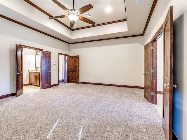 unfurnished bedroom with a tray ceiling, carpet flooring, crown molding, and baseboards