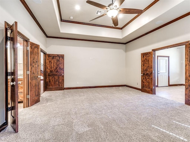 carpeted spare room with a ceiling fan, baseboards, visible vents, a raised ceiling, and crown molding