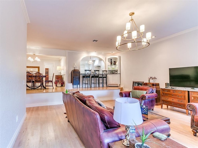 living room with a notable chandelier, ornamental molding, and light wood-type flooring