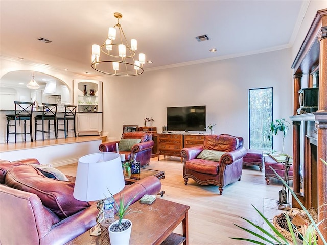 living room featuring ornamental molding, a chandelier, and light hardwood / wood-style floors