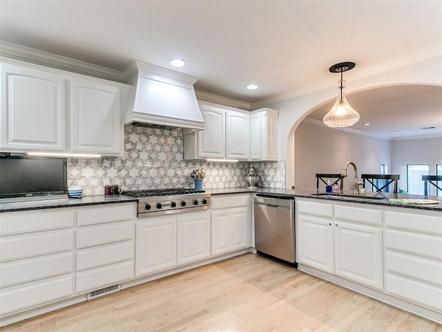 kitchen with sink, white cabinetry, stainless steel appliances, custom exhaust hood, and dark stone counters