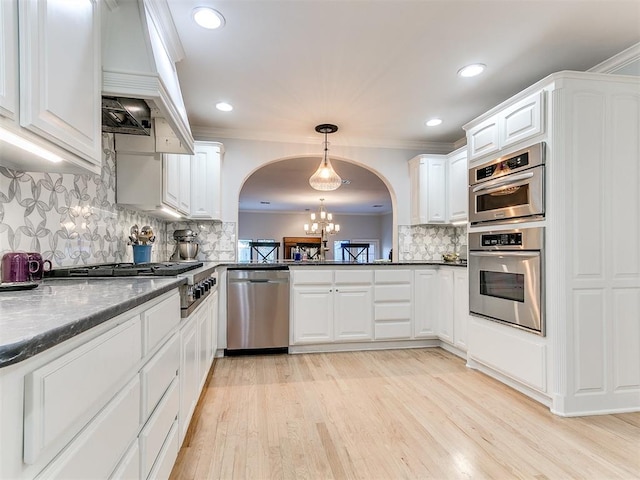 kitchen featuring white cabinetry, dark stone countertops, stainless steel appliances, decorative light fixtures, and a chandelier