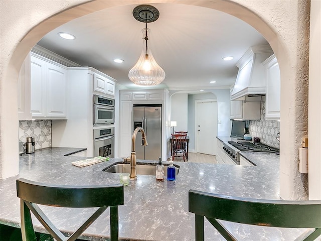 kitchen featuring pendant lighting, sink, appliances with stainless steel finishes, backsplash, and white cabinets