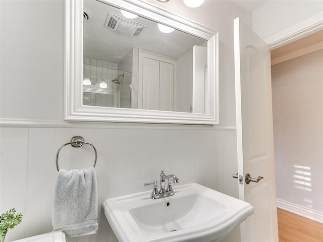 bathroom featuring a tile shower, sink, and wood-type flooring