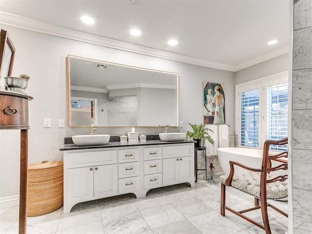 bathroom featuring vanity, ornamental molding, and a bathing tub