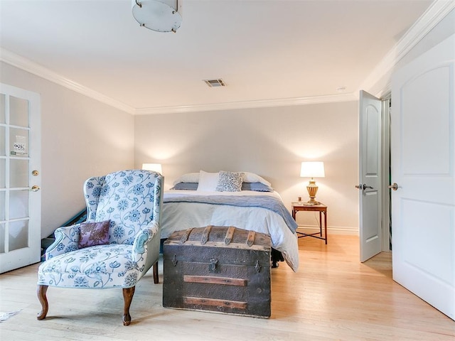 bedroom with baseboards, wood finished floors, visible vents, and ornamental molding