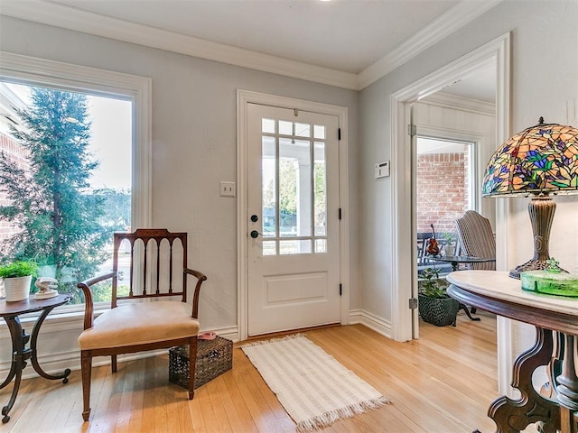 entryway featuring baseboards, light wood-style floors, and ornamental molding