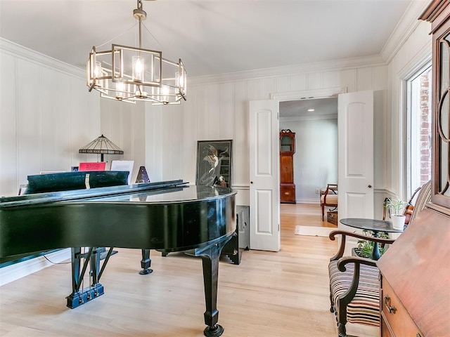 living area featuring light wood-style flooring, a notable chandelier, and ornamental molding