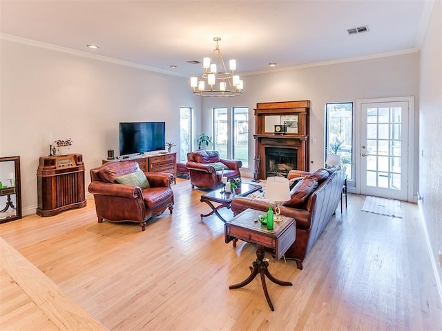 living area featuring a fireplace, visible vents, light wood finished floors, and ornamental molding