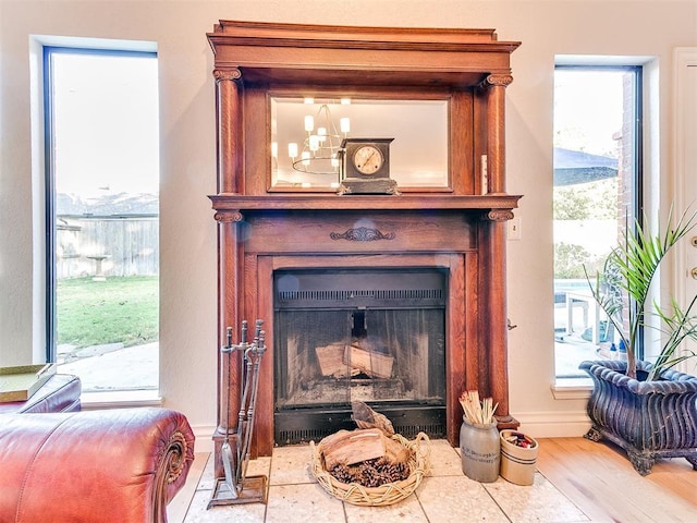 room details featuring a notable chandelier, a fireplace with flush hearth, wood finished floors, and baseboards