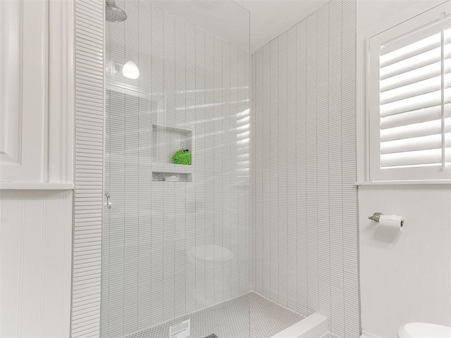 bathroom with toilet and a tile shower