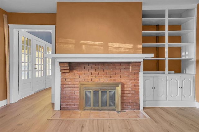 room details featuring a brick fireplace, french doors, and hardwood / wood-style flooring