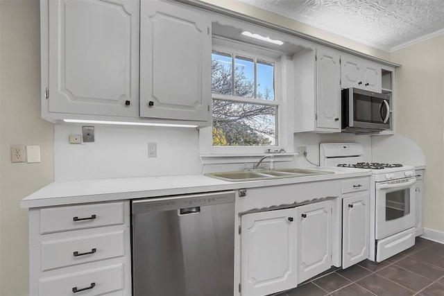 kitchen featuring white cabinets, sink, appliances with stainless steel finishes, and dark tile patterned flooring