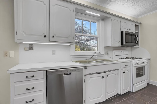 603 N College St, Cordell, OK 73632 - kitchen with appliances with stainless steel finishes, a sink, dark tile patterned flooring, light countertops, and white cabinets