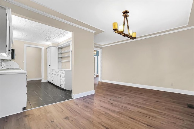 unfurnished dining area featuring built in shelves, dark hardwood / wood-style flooring, an inviting chandelier, and ornamental molding