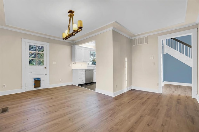 unfurnished living room with plenty of natural light, hardwood / wood-style floors, a notable chandelier, and ornamental molding