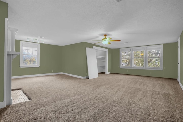 unfurnished living room with ceiling fan, carpet floors, and a textured ceiling