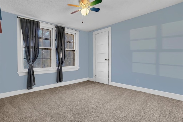 empty room with carpet flooring, ceiling fan, and a textured ceiling