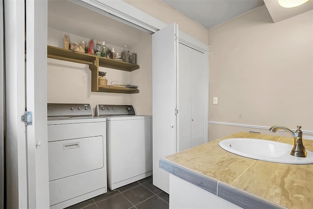 washroom featuring sink, washer and dryer, and dark tile patterned flooring